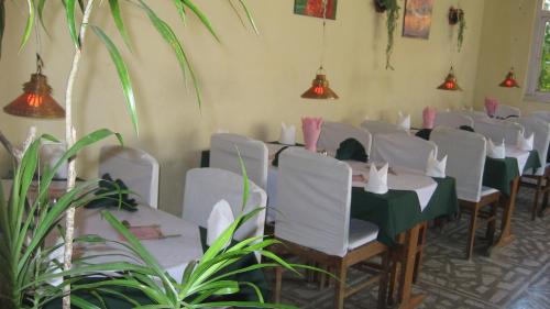 a dining room with white tables and chairs and plants at Hotel Yeti in Pokhara
