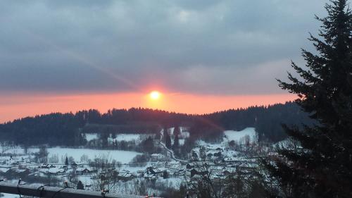 a sun setting over a snow covered village on a mountain at Apartment Abendrot in Sankt Englmar