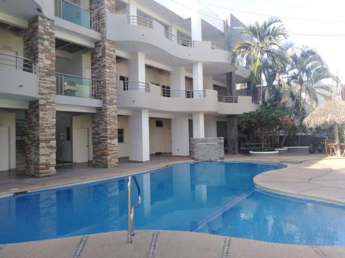 a hotel with a swimming pool in front of a building at Real del Sol in Rincon de Guayabitos