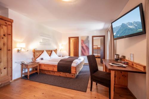 a bedroom with a bed and a desk and a window at Hotel Walchseer Hof in Walchsee