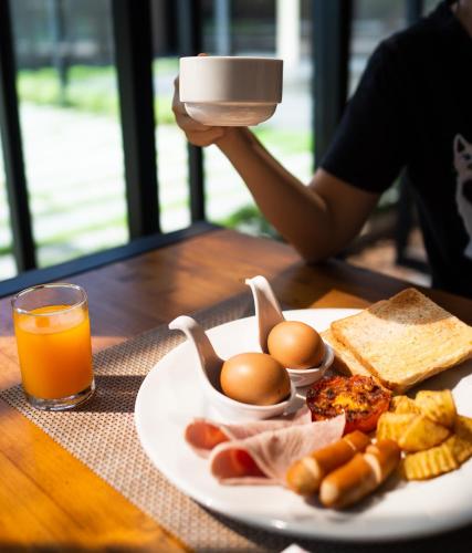 a plate of food with eggs and bread and a glass of orange juice at The Gallery Hotel Nai Harn in Nai Harn Beach