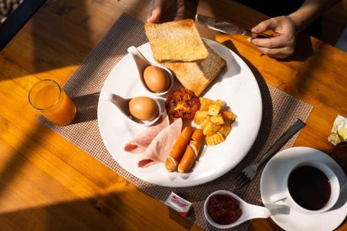 a white plate with eggs meat and bread on a table at The Gallery Hotel Nai Harn in Nai Harn Beach