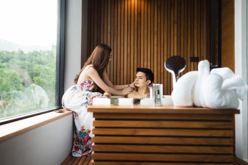 a woman shaving a mans face in front of a mirror at The Gallery Hotel Nai Harn in Nai Harn Beach
