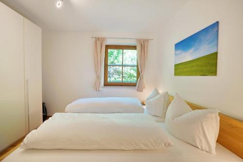 two beds in a white room with a window at Rettenberger Murmele in Rettenberg