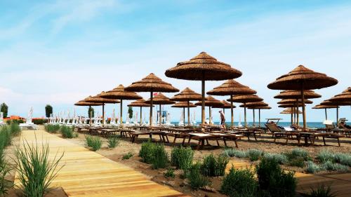 a group of tables and umbrellas on a beach at Lino delle Fate Eco Resort in Bibione