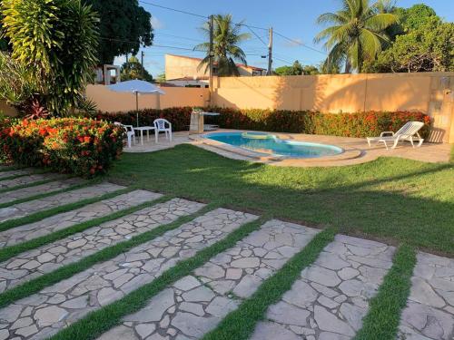 um quintal com uma piscina, uma mesa e cadeiras em Casa na Praia - Parkrio Sauaçuhy - Maceió - AL em Maceió
