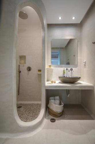 a bathroom with a sink and a shower with a mirror at Naxos Nature Suites in Agios Prokopios