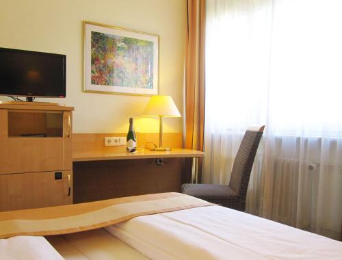a hotel room with a bed and a desk with a television at Motel Frankfurt in Frankfurt/Main