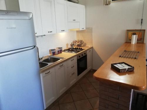 a kitchen with white cabinets and a sink and a refrigerator at Marinelli Guest House in Cisternino