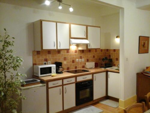 une petite cuisine avec des armoires blanches et un micro-ondes dans l'établissement Séjour provençal, à Dieulefit