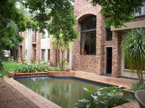 a house with a pond in front of a building at 24 Onvrey Guest House in Boksburg