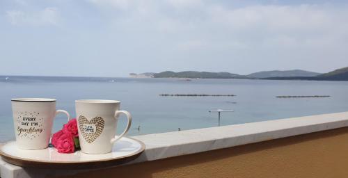 two coffee cups sitting on a tray next to the water at Appartamenti Sole 1 in Alghero