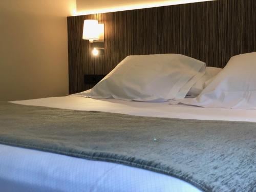 a bed in a hotel room with white sheets and pillows at Hotel Balneario de La Virgen in Jaraba