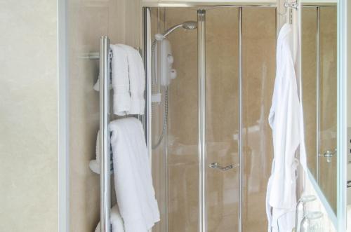 La salle de bains est pourvue d'une douche et de serviettes blanches. dans l'établissement Beera Farmhouse, à Milton Abbot