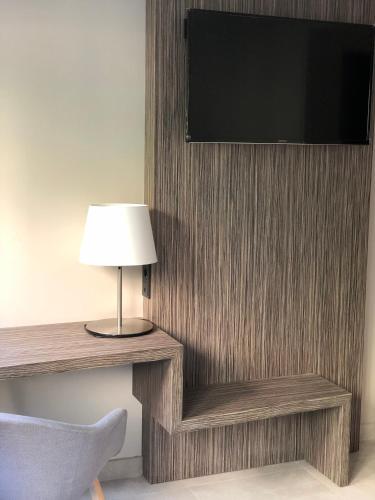 a room with a tv and a lamp and a chair at Hotel Balneario de La Virgen in Jaraba