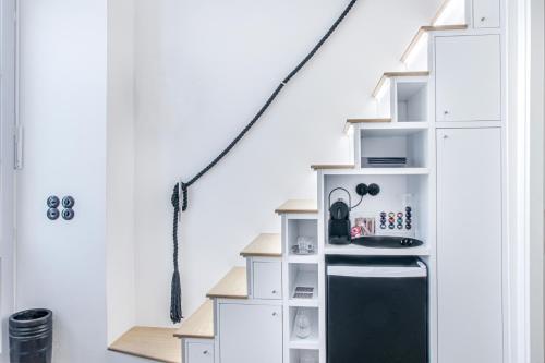 a kitchen with white cabinets and a black refrigerator at Clock Wise Syros in Ermoupoli