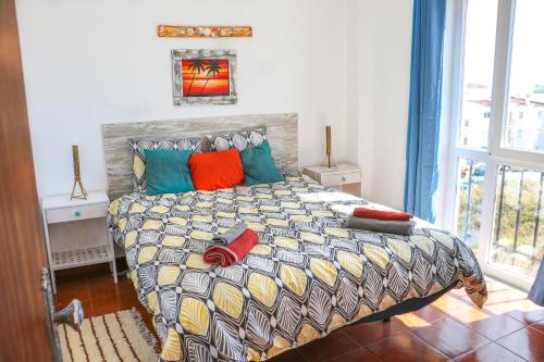 um quarto com uma cama grande e almofadas coloridas em Casa Bambu Luz na Praia da Luz