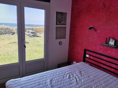 ein Schlafzimmer mit einer roten Wand und ein Bett mit einem Fenster in der Unterkunft Das Haus auf der Düne in Plouescat
