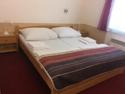 a bed with two pillows and a blanket on it at Pension Miltom in České Budějovice