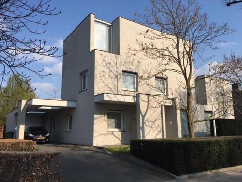 a white house with a car parked in front of it at Bed & Wellness Boxtel, luxe kamer met airco en eigen badkamer, ligbad in Boxtel