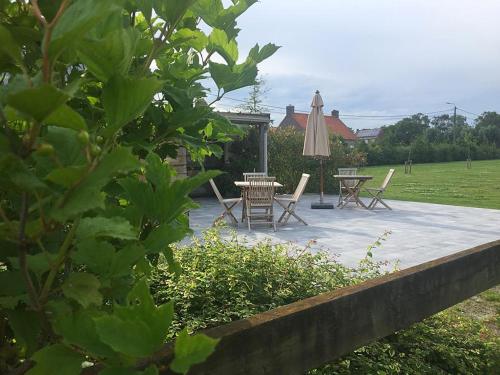 Hooglede的住宿－B&B Gitsdal，庭院配有桌椅和遮阳伞。