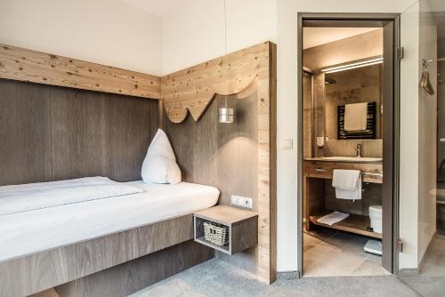 a bedroom with a bed and a bathroom with a sink at Dips&Drops - First Bike & Ski Hub in Flachau