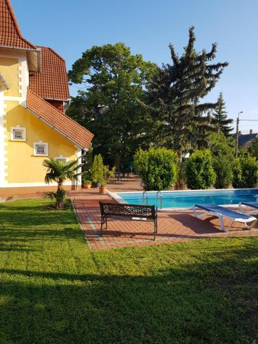 a bench next to a house with a swimming pool at Éden Villa Apartmanház in Balatonfüred