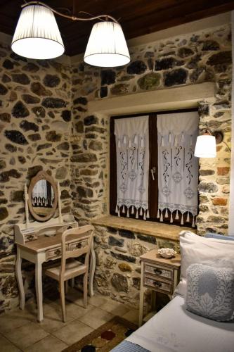 a bedroom with a stone wall with a bed and a desk at Millers Guest House in Kalyves Poligirou