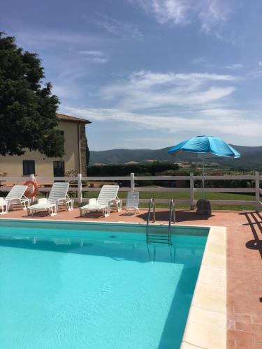 a swimming pool with chairs and an umbrella at Casale Poggio Meone in Santa Luce