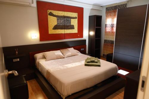1 dormitorio con 1 cama y una pintura en la pared en The Victoria Apartament in Hellín, en Hellín