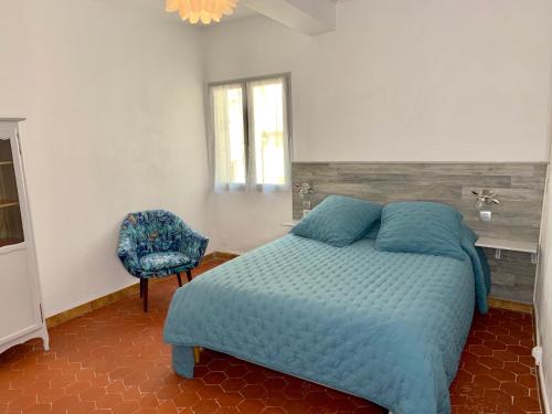 a bedroom with a blue bed and a chair at Appartement l’étoile in Moustiers-Sainte-Marie
