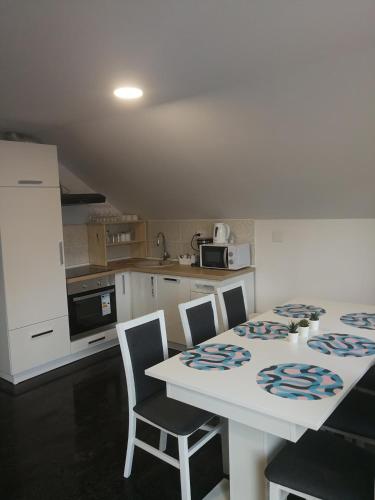 a kitchen with a white table with chairs and a counter at New apartment near Plitvice lakes in Smoljanac