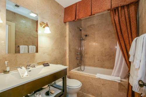 a bathroom with a sink and a toilet and a tub at Harvey House Bed & Breakfast in Oak Park