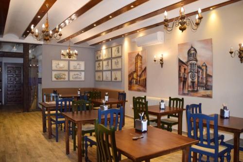 un restaurante con mesas de madera y sillas azules en HOSTAL RESTAURANTE SAN ISIDRO en Quintanar de la Orden