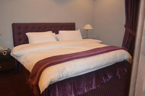 a large bed with white sheets and pillows at Carlton Tower Hotel Kuwait in Kuwait