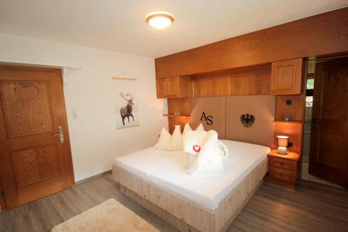 a bedroom with a white bed with wooden cabinets at Gästeheim Anna in Längenfeld