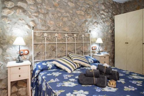 奧羅佩薩德爾馬的住宿－L'Atalaya D'or，一间卧室设有床、两个床头柜和石墙