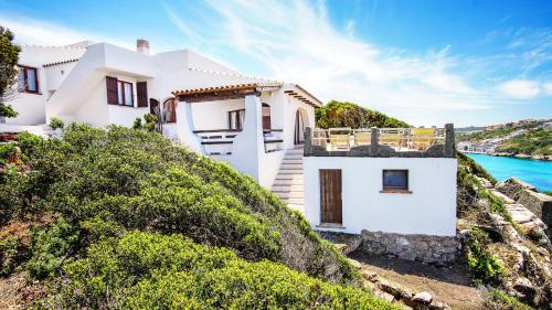 Ein weißes Haus auf einem Hügel neben dem Wasser in der Unterkunft Villa Elena B&B experience in Santa Teresa Gallura