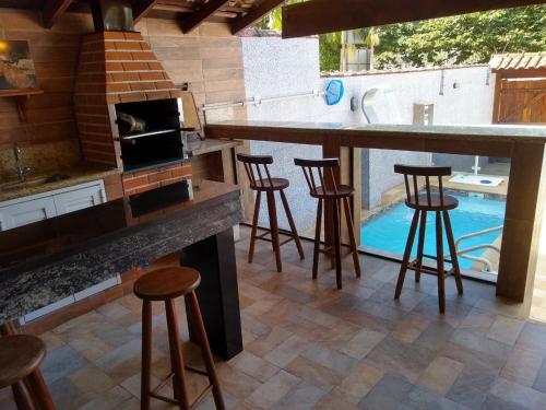 uma cozinha com um bar com bancos e uma piscina em Casa Piscina Azul em Paraty