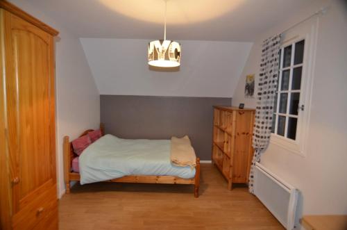 Habitación pequeña con cama y lámpara de araña. en CHAMBRES chez L'HABITANT, en Saint-Paul-du-Vernay