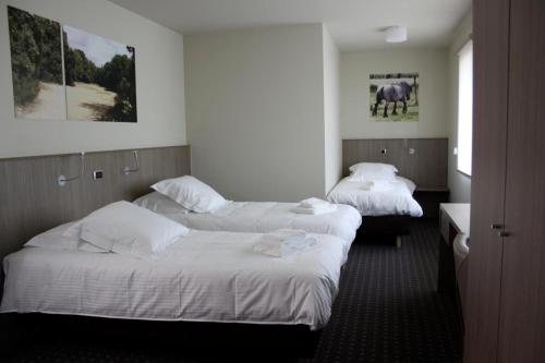 Hotel Otus في Wetteren: سريرين في غرفة الفندق ذات شراشف بيضاء
