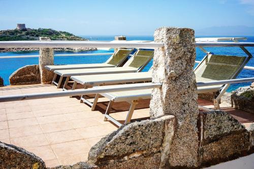 a row of lounge chairs on a patio with the ocean at Villa Elena B&B experience in Santa Teresa Gallura