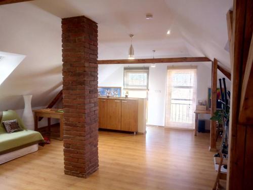 a living room with a brick pillar and a kitchen at Podkroví s koupelnou in Svinařov