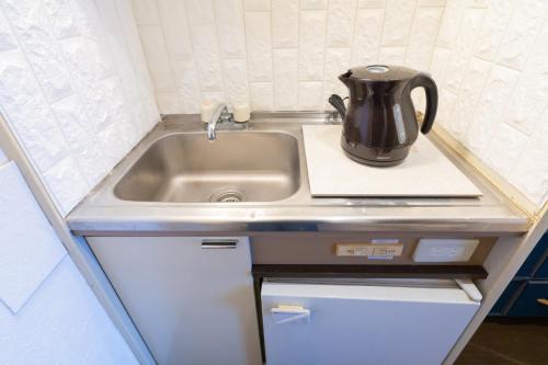 uma cozinha com um lavatório e uma chaleira de chá no balcão em Dazaifu - Apartment / Vacation STAY 36942 em Dazaifu