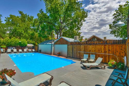 a swimming pool with chairs and a fence at Rustic Inn in Moab