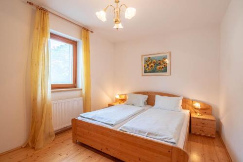 a bedroom with a bed with white sheets and a window at SportApartment Wabnig in Moosburg