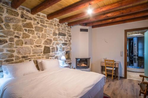 ein Schlafzimmer mit einem Bett und einer Steinmauer in der Unterkunft Hotel Arhontiko Vourloka in Pramanta