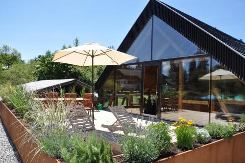a house with a patio with chairs and an umbrella at Ferienwohnung Reichart in Lochau