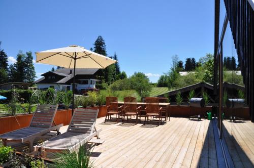 a deck with chairs and a table and an umbrella at Ferienwohnung Reichart in Lochau