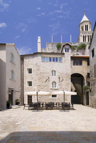 a patio with tables and umbrellas in front of a building at Hotel Vestibul Palace & Villa - Small Luxury Hotels Of The World in Split